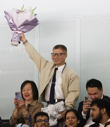 A supporter holds up a bouquet of flowers during a convocation ceremony