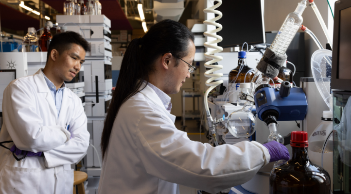 Two people in lab coats look at some equipment