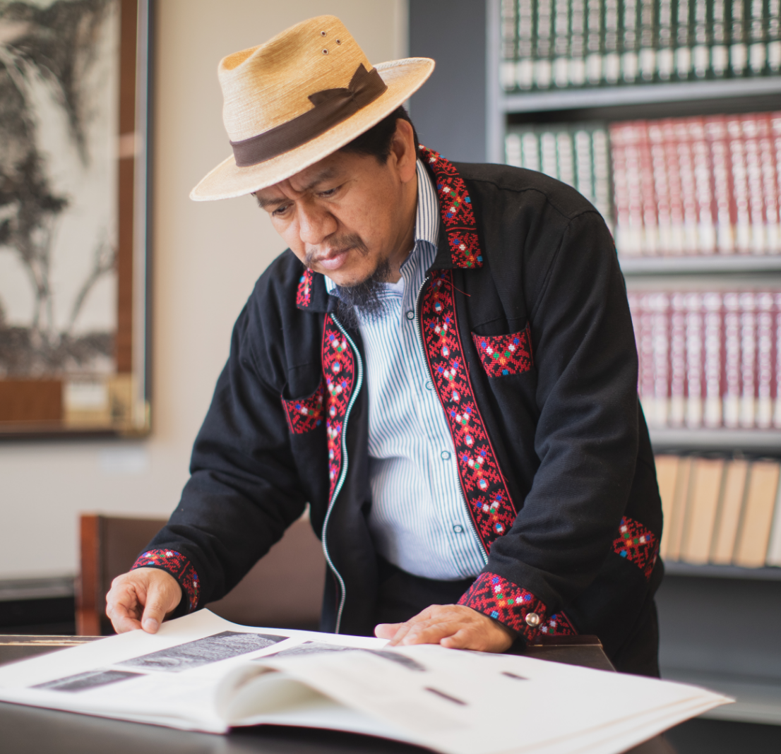 A man looks at a large book on a table