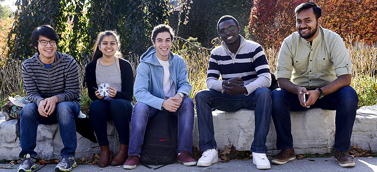 Five students sit together outside