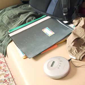 duotangs and a portable cd player and a backpack on a seat