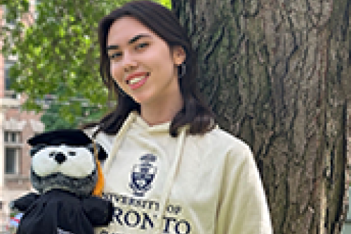 A student holds a stuffed toy convocation owl
