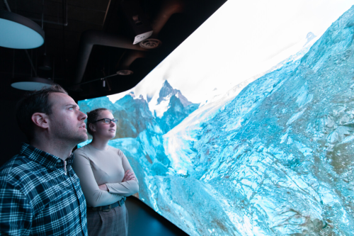 Two people look up at a wall-sized screen
