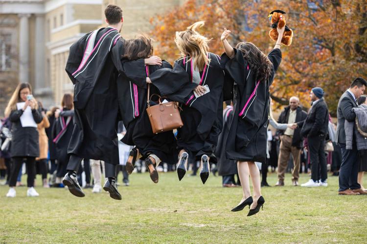 graduands jumping for joy in front of convocation hall