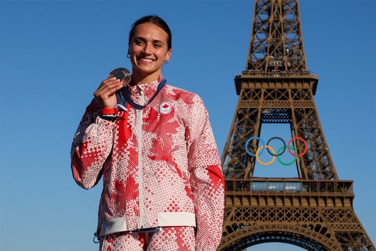 Kyli Masse holds up her bronze medal in front of the Eiffel Tower at the 2024 summer olympics