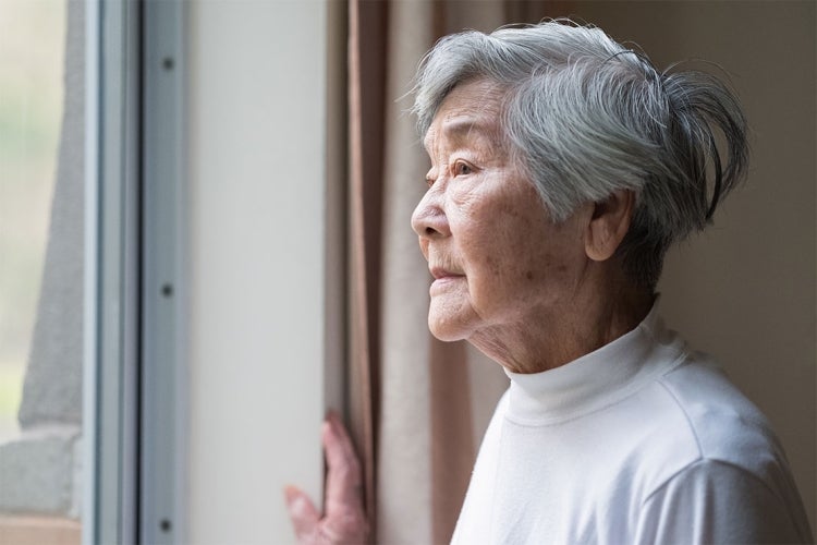 An asian woman looks out a window