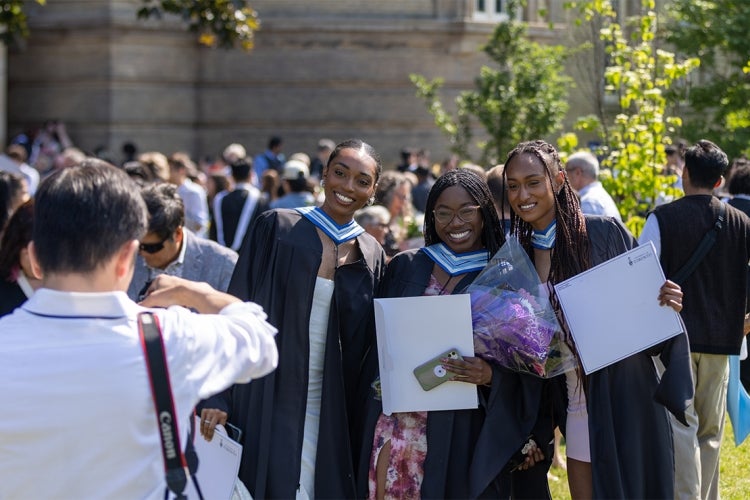 Three grads hold up their degrees while posing for a photo