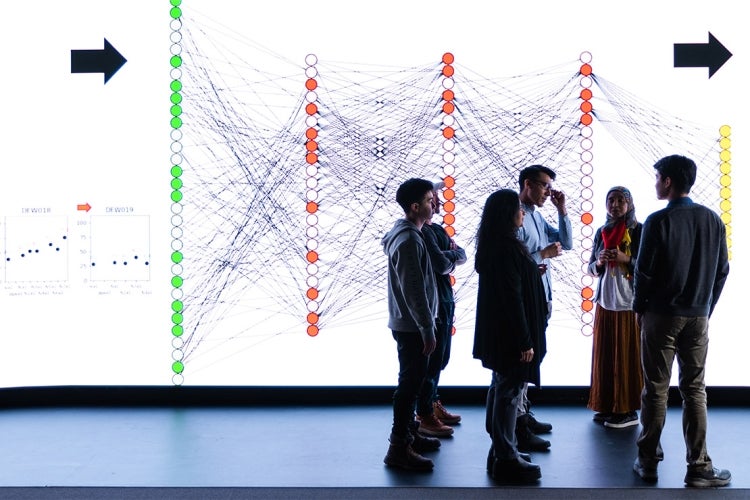 an instructor and students in front of a large visualization screen at the university of toronto