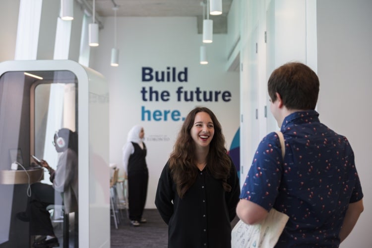 People inside the ONRamp corworking space with "build the future here" written on the wall behind