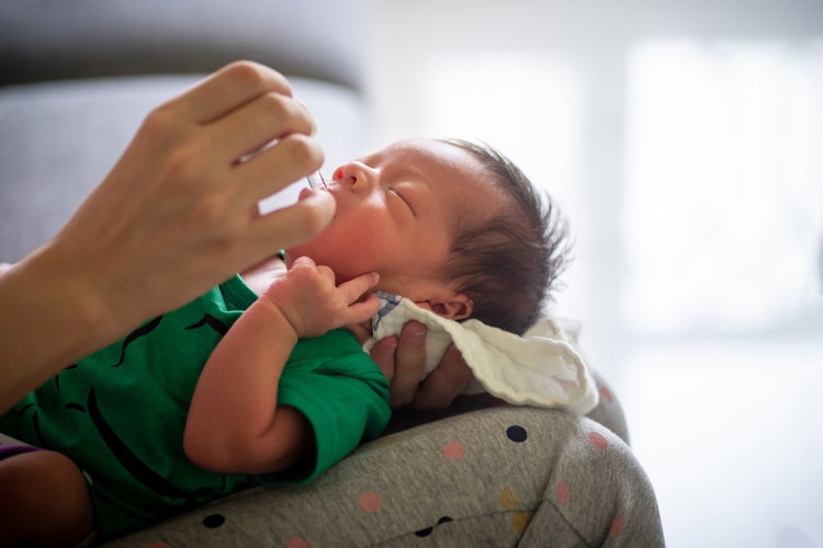 infant being fed medication with a small tube