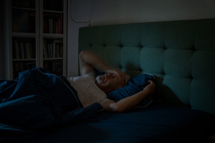 older man having trouble sleeping in bed