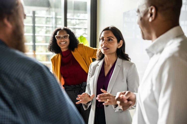 A team lead speaks to other workers in an office environment