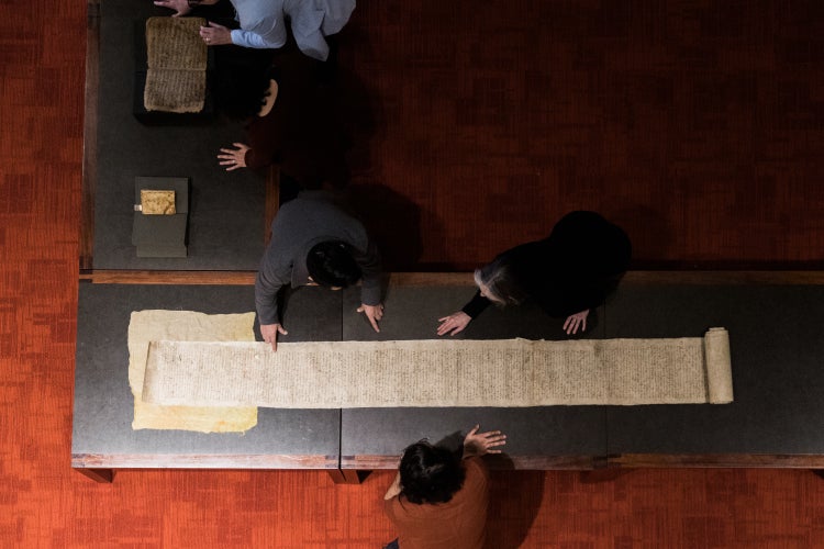 Students look at a long scroll in the Fisher Rare Book Library