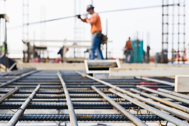 worker carrying rebar with rebar in the foreground