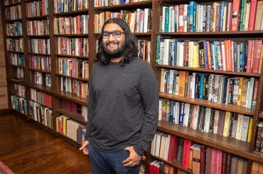 Portrait of incoming PhD student Seshu Iyengar shot in front of a row of bookshelves