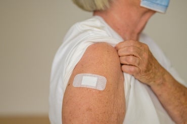 an elderly woman with a band aid on her arm after being vaccinated