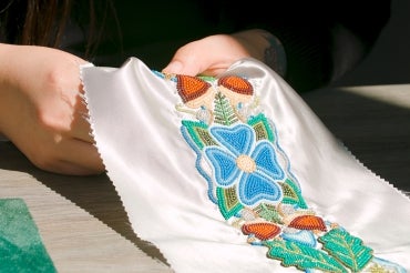 Close up of Katie Longboat's hands beading a stole