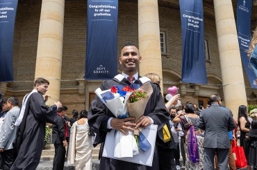 Jaivet Ealom stands in front of Convocation Hall after his graduation ceremony