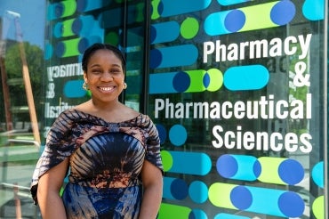 Theodora Udounwa stands outside the Pharmacy building signage