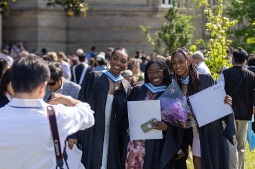 Three grads hold up their degrees while posing for a photo