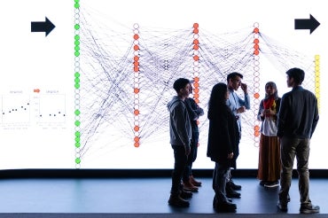 an instructor and students in front of a large visualization screen at the university of toronto