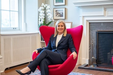 president melanie woodin sits in a large red chair in her office