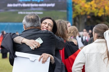 A graduand gives an emotional hug to a an older man following the convocation ceremony at the University of Toronto