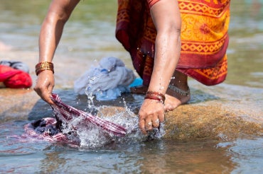 woman handwashing clothes in river