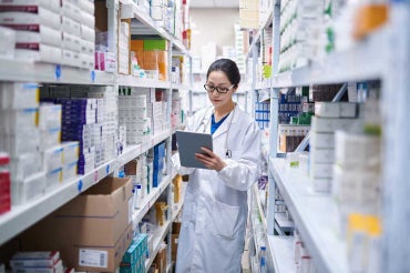 a female pharmacist checks inventory on pharmacy shelves