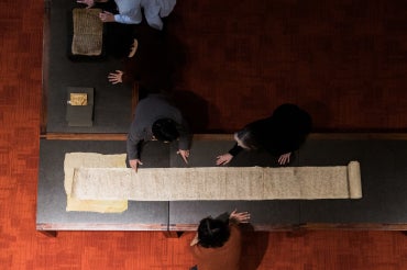 Students look at a long scroll in the Fisher Rare Book Library