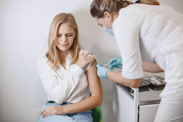 young woman gets a needle at a doctor's office