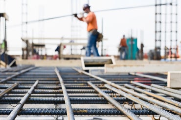 worker carrying rebar with rebar in the foreground