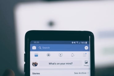 close up of smartphone with facebook app up. Text on screen reads "what's on your mind?"