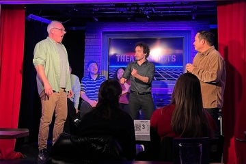 Robert-Tahiri on stage with a couple of volunteers