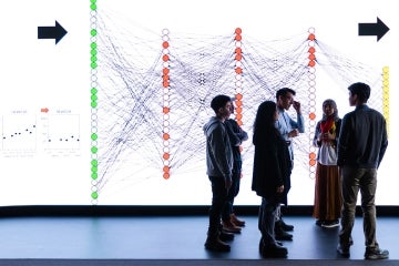 an instructor and students in front of a large visualization screen at the university of toronto