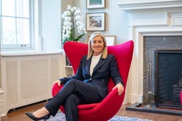 president melanie woodin sits in a large red chair in her office