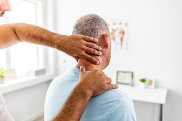an older man has his neck and spine examined by a doctor in a doctors office
