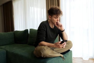 young adult male looking pensively at his phone