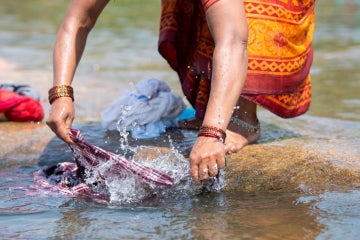 woman handwashing clothes in river