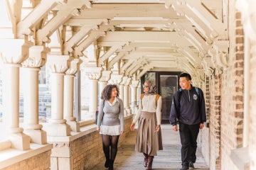 three students walking through a walkway in the University College quad at the University of Toronto