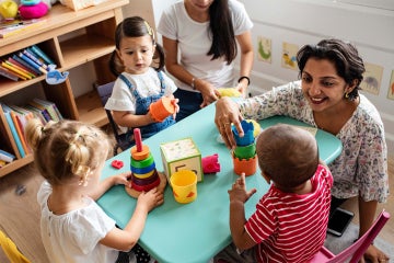 A woman engaging with 3 toddlers in a day care setting