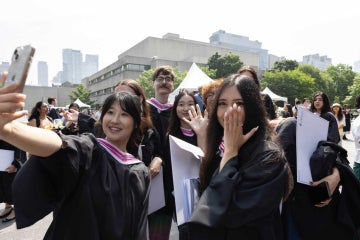 graduating students smile while taking a selfie outside of convocation hall 