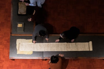Students look at a long scroll in the Fisher Rare Book Library