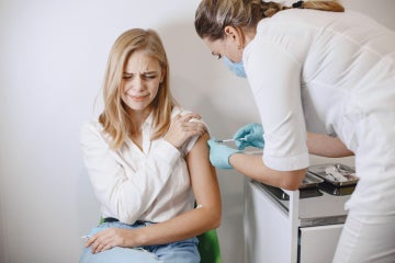 young woman gets a needle at a doctor's office