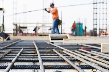 worker carrying rebar with rebar in the foreground