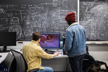 two students looking at a computer screen and practicing remote surgery