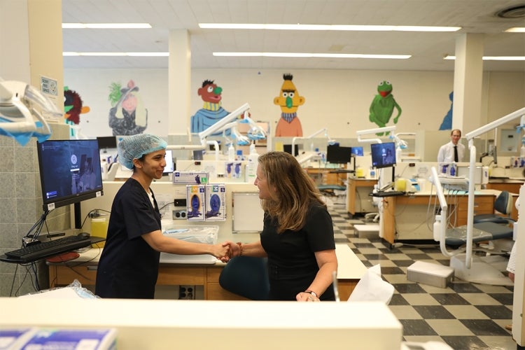 Freeland shakes hands with a student in the children's dental clinic